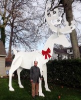 Coaster Photo - Professional woodworker Dave Gallina stands by his 15-foot-high wooden reindeer on his front lawn in the West Allenhurst section of Ocean Township.