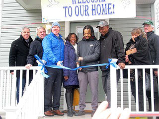 Coaster photo - Christian Cortez, a resident of Meg’s Place, cuts the ribbon at the Rights of Passage Home dedication in Asbury Park. From left are: Jim White, Executive Director, Covenant House; Asbury Park Mayor John Moor; President of Covenant House International, Kevin Ryan; Councilwoman Yvonne Clayton; Councilman Jesse Kendle, Youth Specialist at Interfaith Neighbors, Meg Flores and Co-Executive Director of Interfaith Neighbors, Paul McEvily.